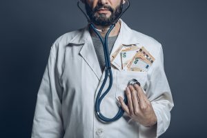 A doctor is listening to his own heart with stethoscope with bills in his pocket