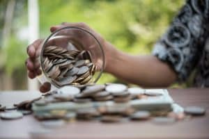 Hand putting coins in jar with money stack step growing growth saving money